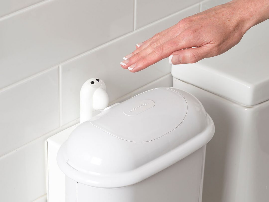 A person holding hand over sensor to activate opening on Pod Petite Auto touch-free sanitary napkin bin