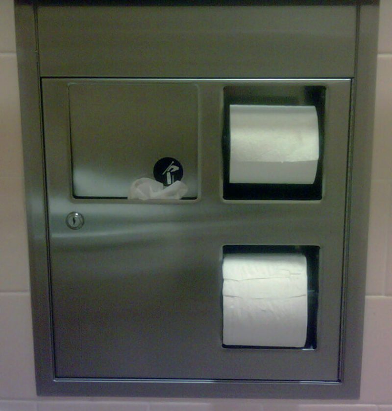 A wall recessed sanitary disposal receptacle in USA overflwoing with feminine hygiene waste