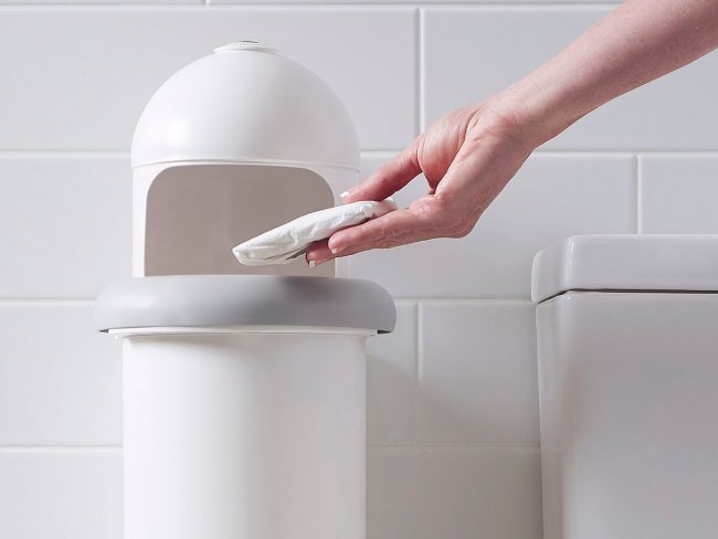 A person disposing sanitary waste into Pod Classic sanitary pad disposal manual unit