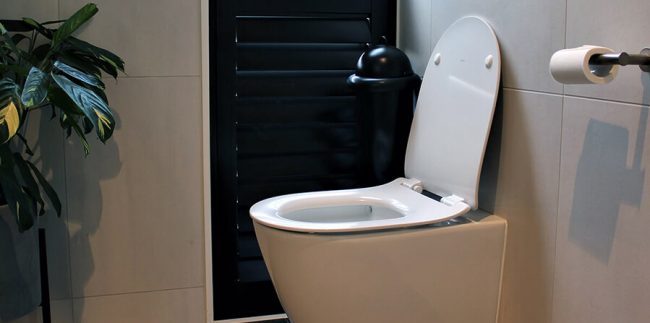 A washroom image with black Pod Classic Mini Manual unit wall-mounted on tiled wall
