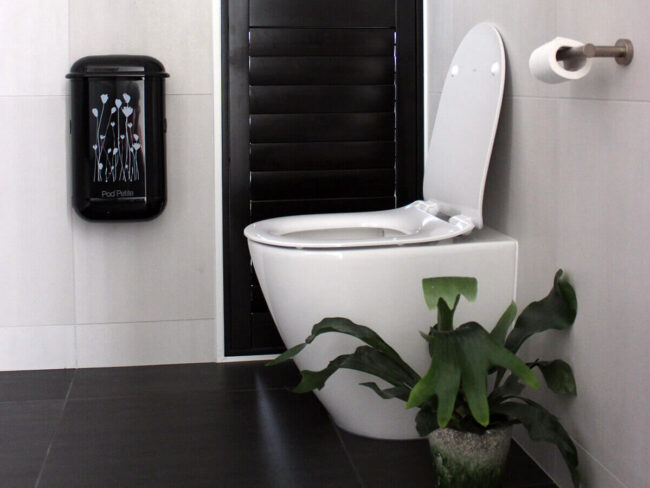 A sleek black Pod Petite sanitary disposal unit with a Pod Wrap Poppies decal.