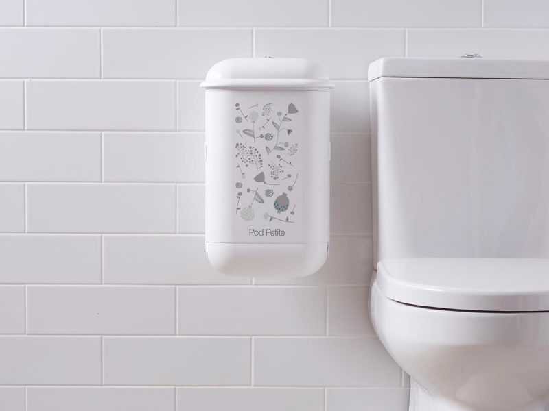 A white Pod Petite sanitary disposal unit with a Pod Wrap Woodland decal.