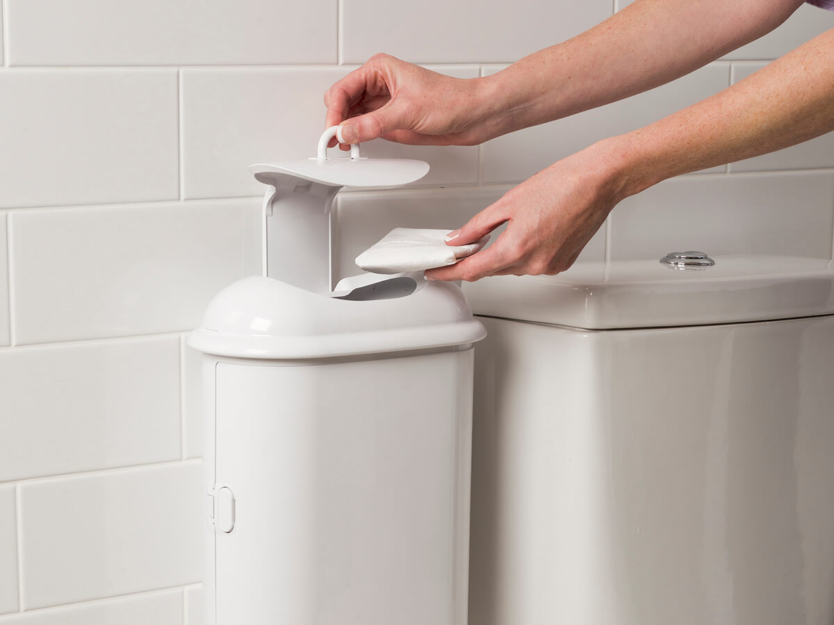 A person disposing sanitary waste into Pod Petite sanitary pad disposal manual unit