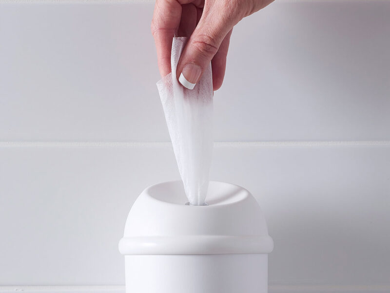 A white Wet Wipe dispenser with hand pulling antimicrobial wet wipe out