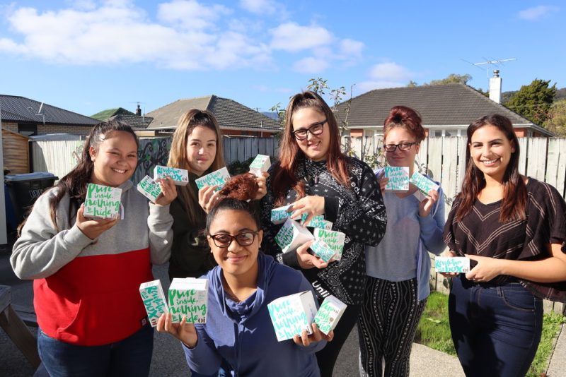 A group of women holding up period products donated from Dignity NZ