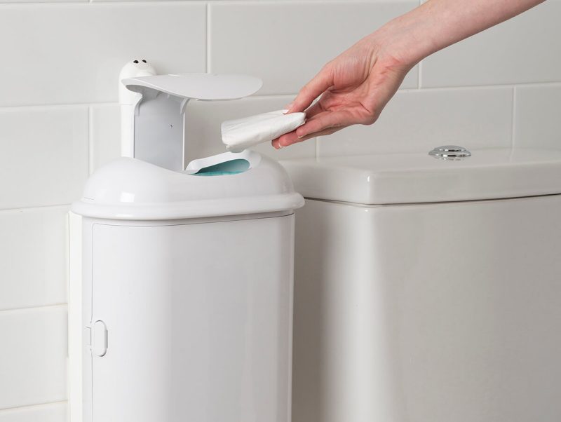 A person placing period waste into an open touch-free Pod Petite Auto sanitary disposal unit