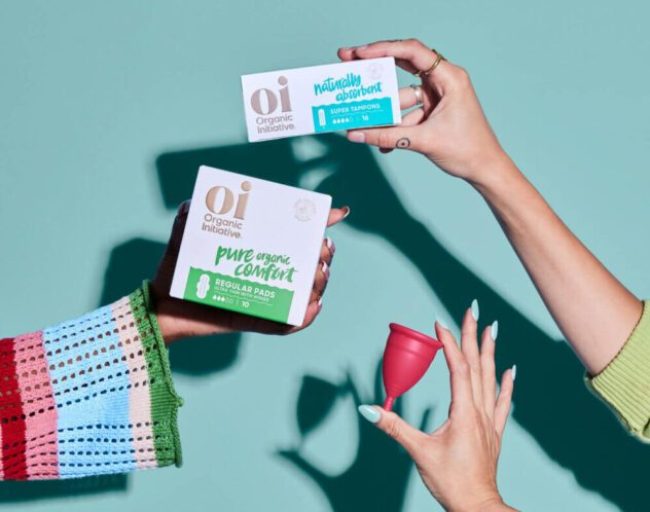 A range of period products being held with womens hands with a mint green background