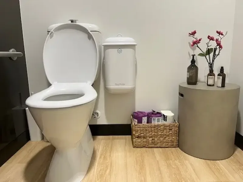 Pod Petite white sanitary disposal unit in bathroom with flowers on side table