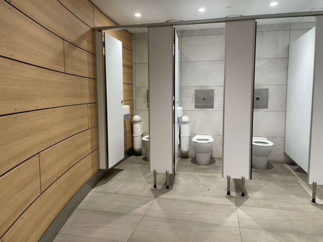 SaniPod Pod Classic Auto White sanitary disposal units in restroom cubicles