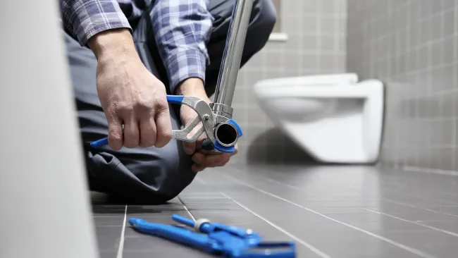 Plumbing costs – plumber working on bathroom