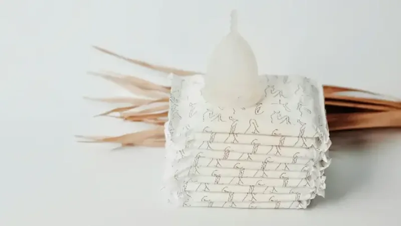 What are feminine hygiene products - Photograph of menstrual cup on top of menstrual pads