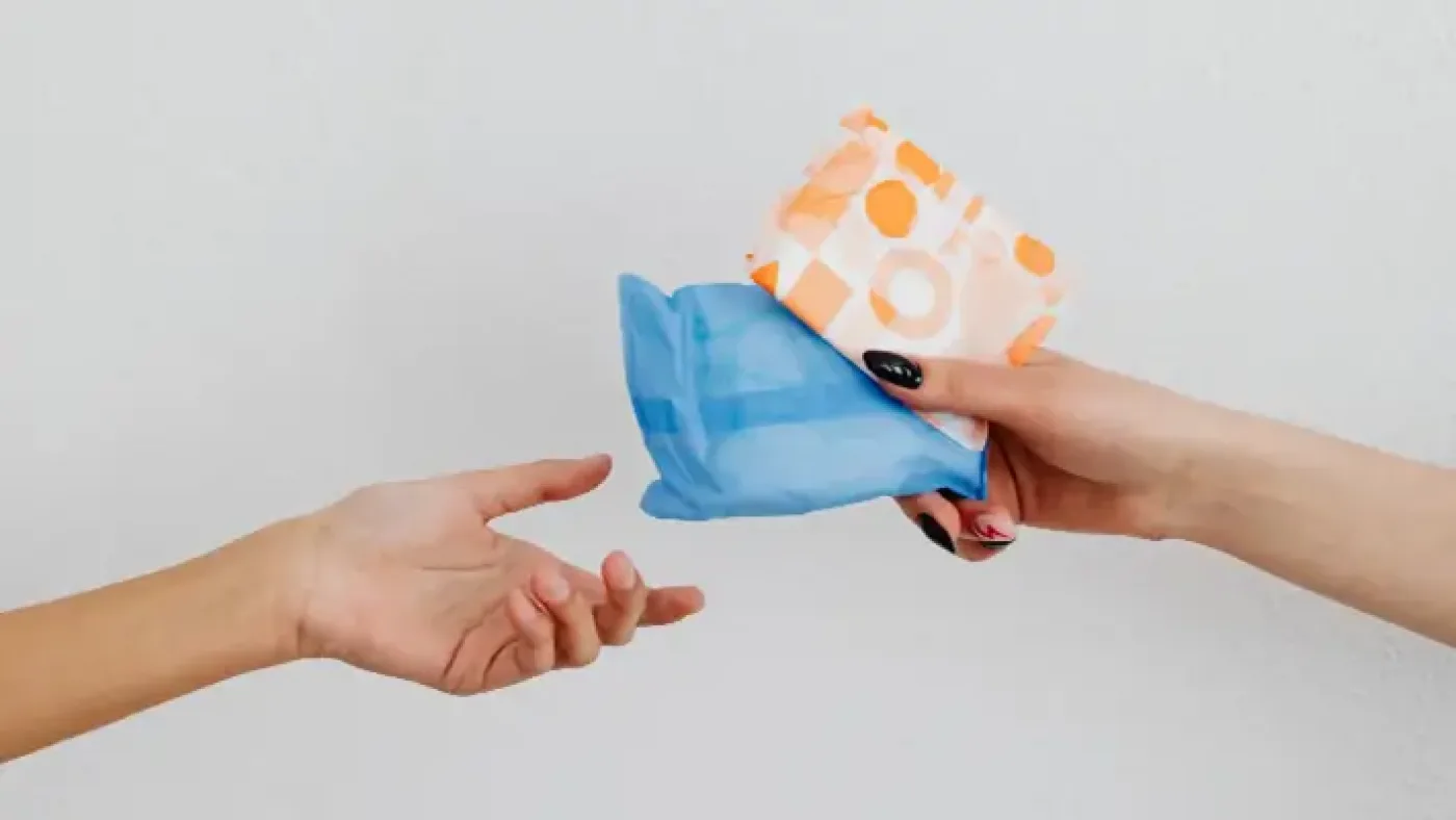 Period poverty USA - close-up of hands exchanging sanitary pads