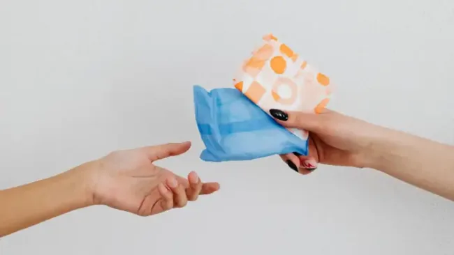 Period poverty USA - close-up of hands exchanging sanitary pads